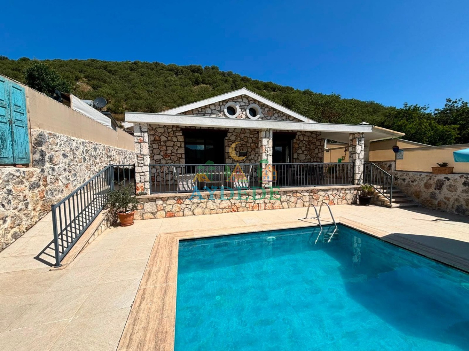 Villa Facer 1’in özel yüzme havuzu ve taş mimarili dış cephesi. Fethiye Kayaköy’de muhafazakar konseptli kiralık tatil villası.