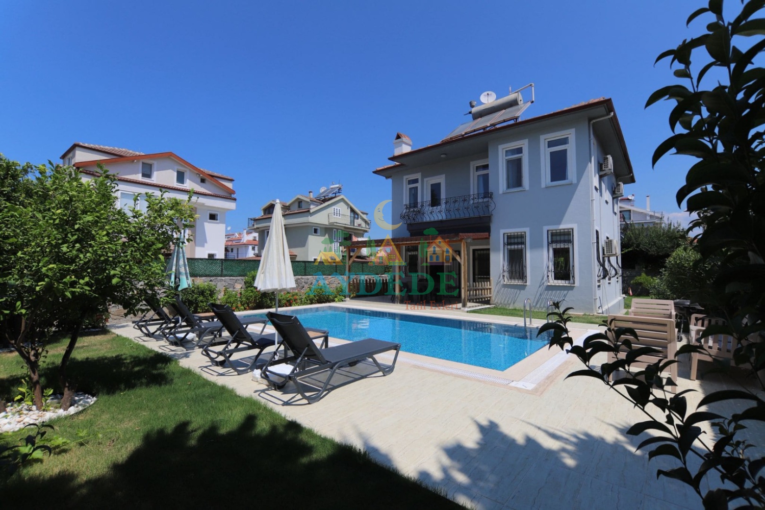 Villa Casa Olive'ın özel yüzme havuzu ve geniş bahçe alanının genel görünümü. Fethiye Merkez'de konumlanan villa, ailelere konforlu ve huzurlu bir tatil deneyimi sunmaktadır.