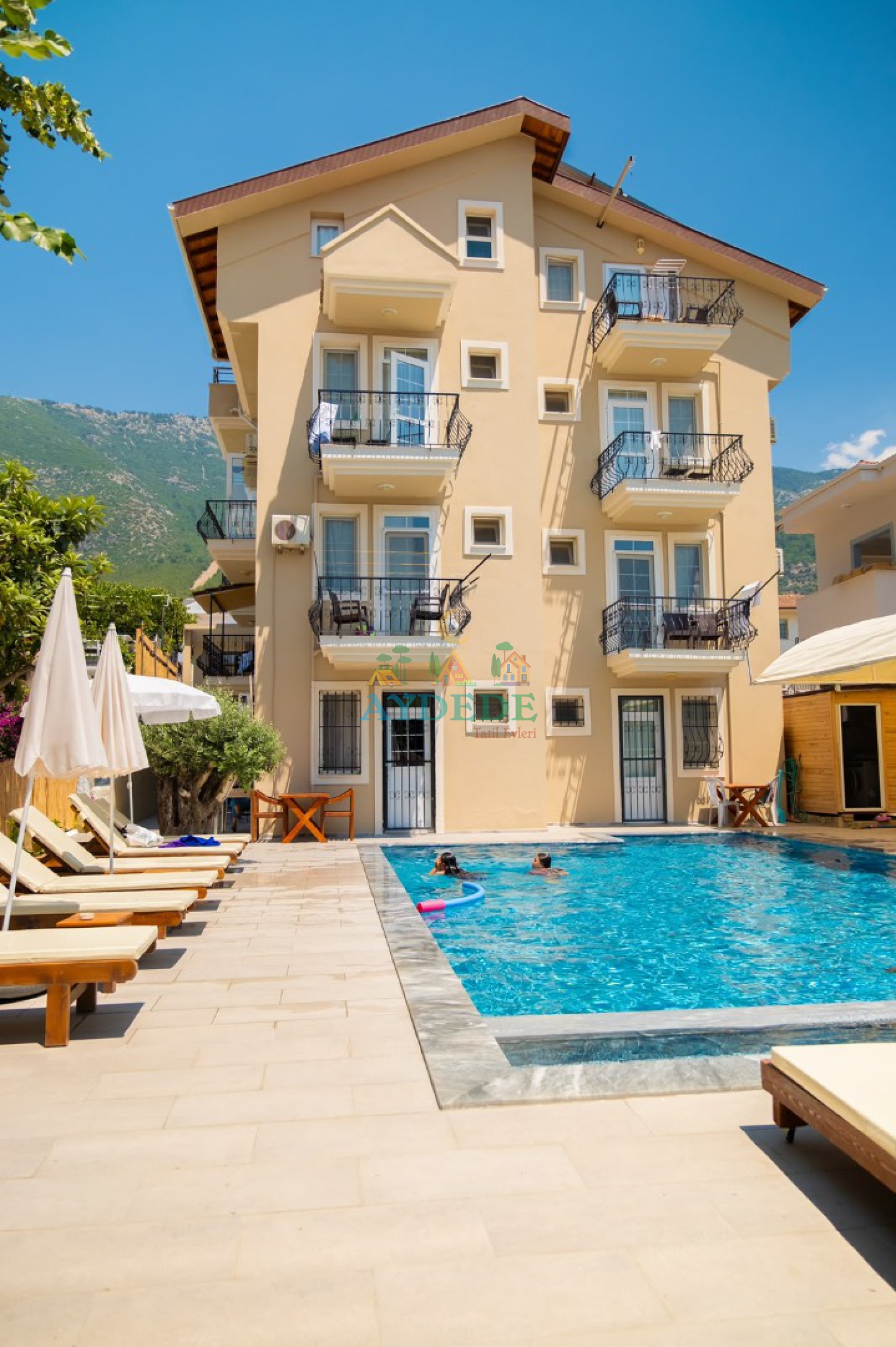 Fethiye'de ortak yüzme havuzuna sahip konforlu apart otel dış cephe görünümü ve güneşlenme alanı.