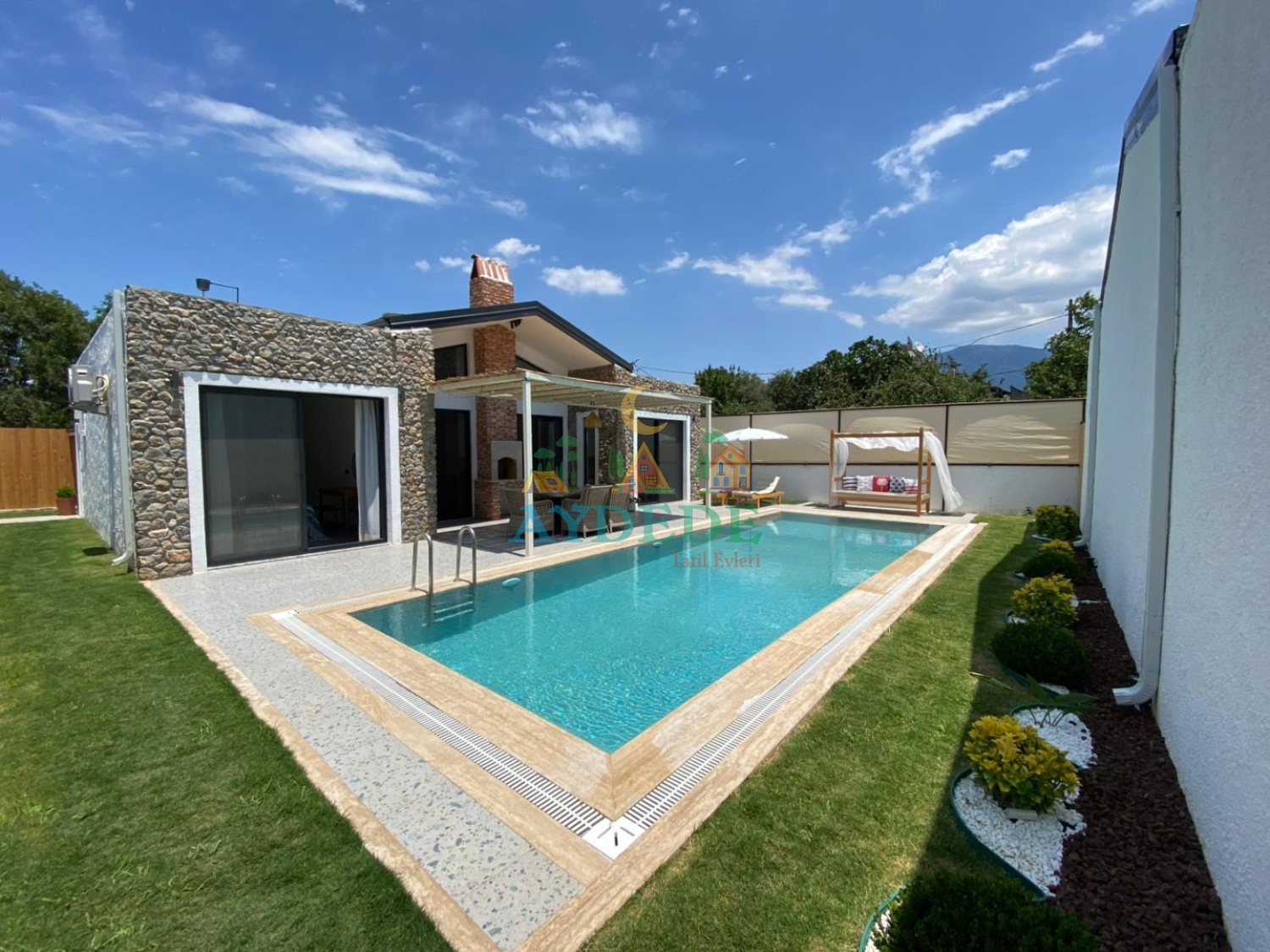 Villa Olipos'un Fethiye Kayaköy'de yer alan özel yüzme havuzu, geniş bahçesi ve modern taş mimariye sahip dış cephesi.