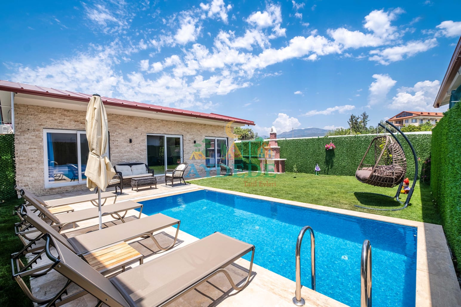 Villa Vimo Fethiye Çiftlik’te özel yüzme havuzu, tek katlı taş mimarisi ve geniş yeşil bahçesiyle huzurlu tatil villası görünümü.