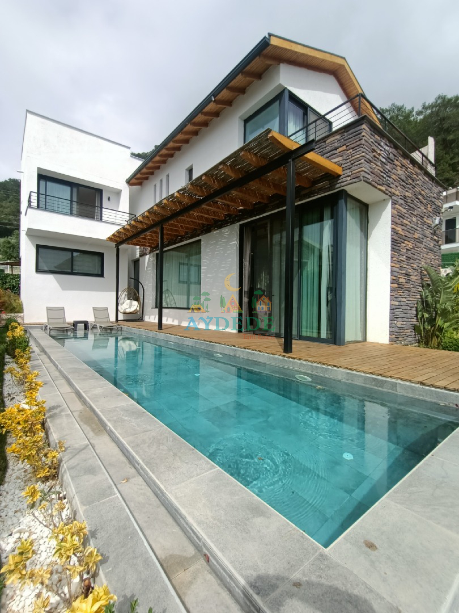 Villa Twins 20 Fethiye Faralya’da modern taş mimarisi, özel yüzme havuzu ve geniş dış yaşam alanıyla lüks villa görünümü.