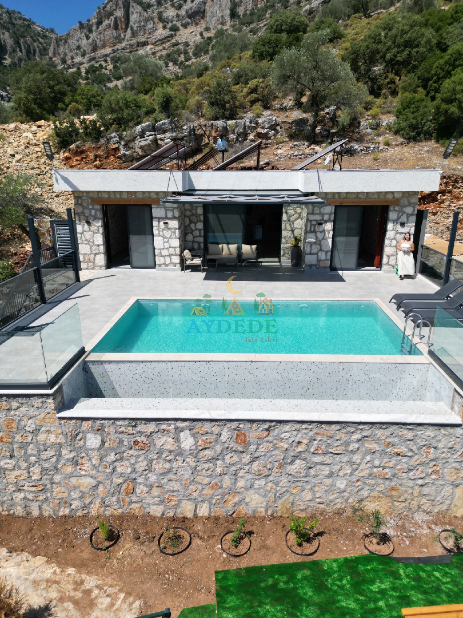 Villa Karahan’ın korunaklı özel yüzme havuzu ve modern taş mimarisi ile doğa manzarasını bir araya getiren dış cephe görünümü.