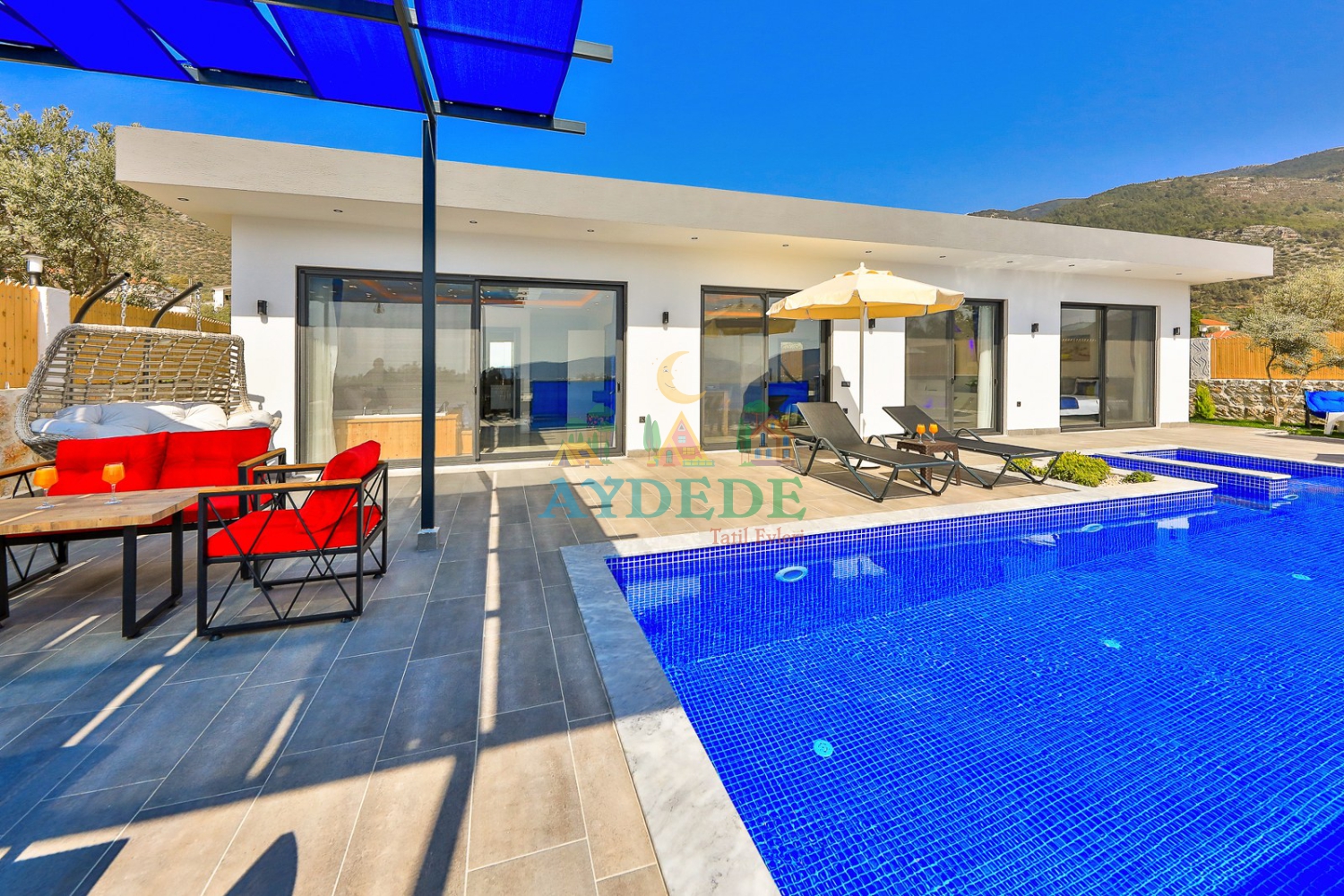 Modern villanın geniş güneşlenme alanı ve şezlongları.