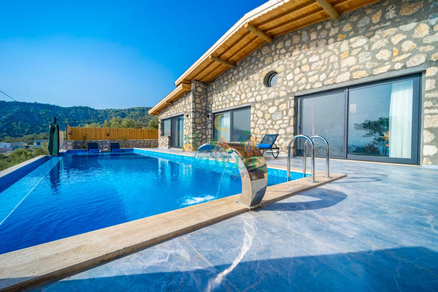 Özel havuzlu kiralık lüks taş villanın dıştan görünümü. Akdeniz mimarisi ve deniz manzarası bir arada.