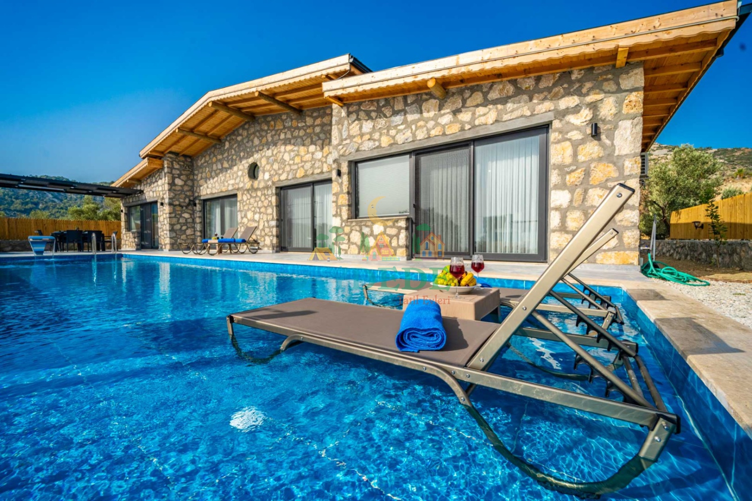 Özel havuzlu kiralık lüks taş villanın dış cephe ve havuz başı görünümü.