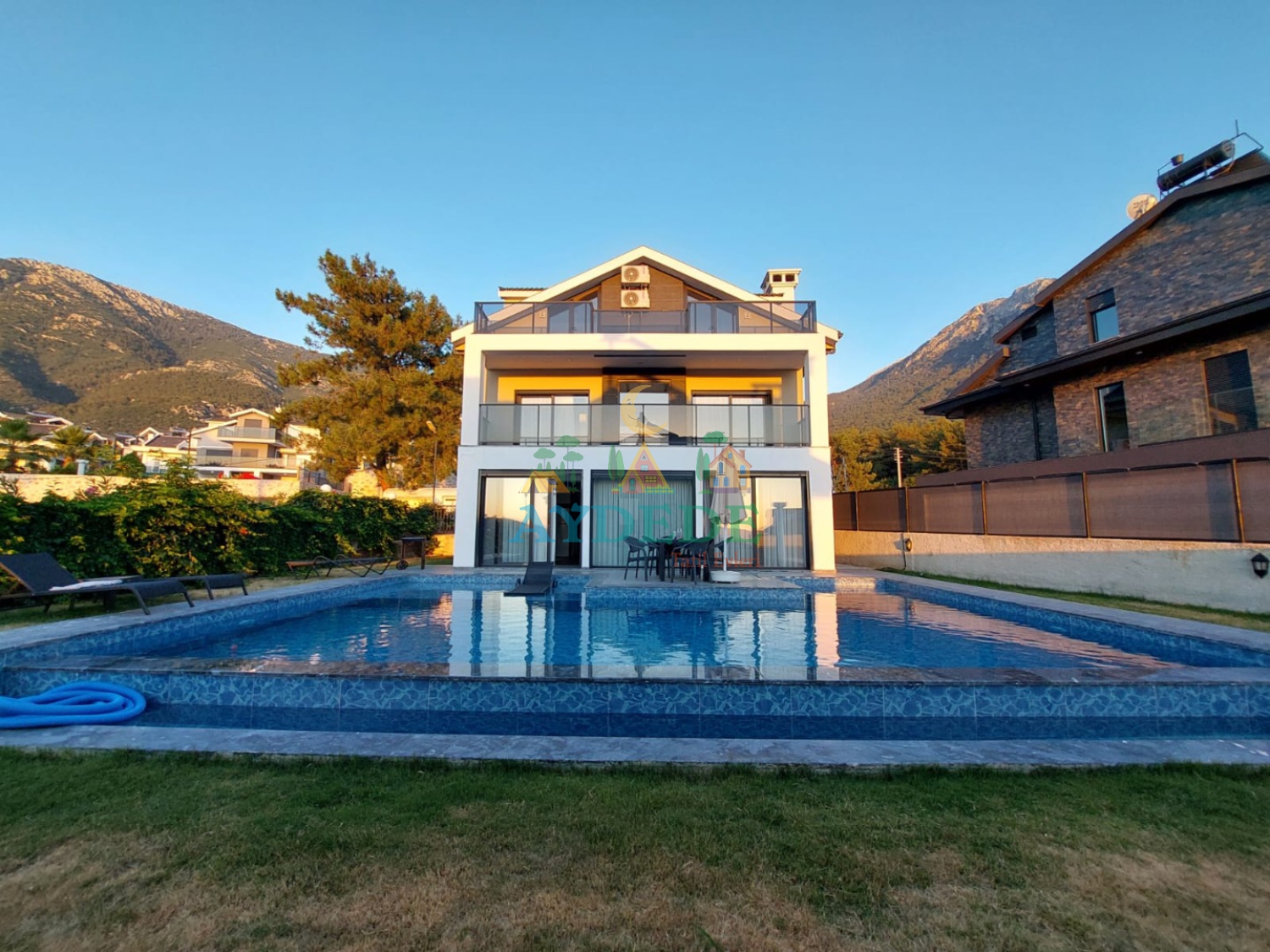 Fethiye Ölüdeniz’de Babadağ manzaralı, geniş özel yüzme havuzuna ve bahçeye sahip müstakil lüks kiralık villa exterior görünümü.
