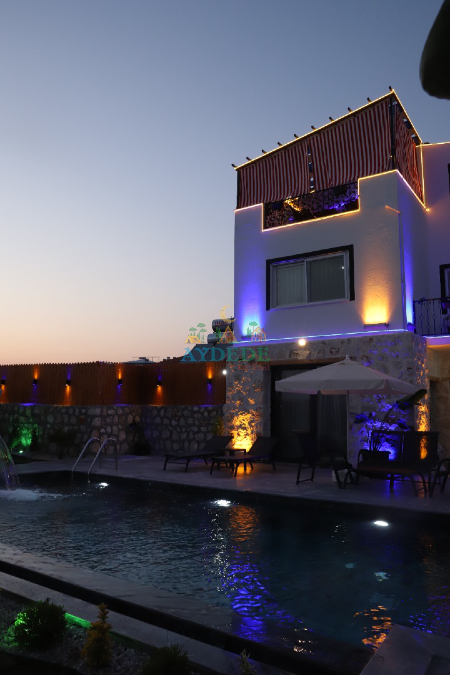 Kalkan Çavdır'da taş mimarisi, renkli LED dış ışıklandırmaları ve özel yüzme havuzuyla Villa Thor'un gece görünümü.